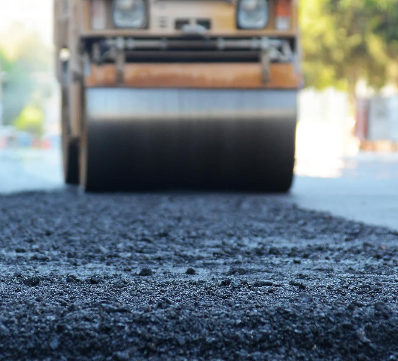 asphalt-overlay-img2 Close-up of fresh asphalt being compacted by a steamroller on a road under construction.